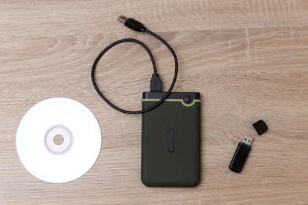 Digital custodians of information. External hard drive, cd and usb flash drive on a wooden tableの写真素材
