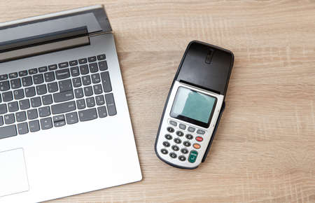 Laptop with Payment pos terminal on a wooden tableの写真素材