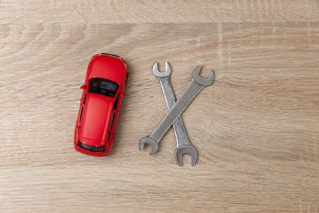 Toy car model with wrench on wooden table. Auto service, repair concept.の写真素材