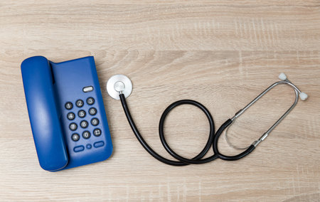 Office landline phone and stethoscope on wooden tableの写真素材