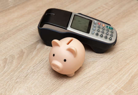 Piggy bank with Payment pos terminal on wooden tableの写真素材