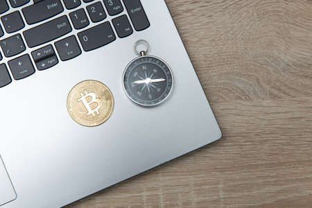 Bitcoin with compass on laptop keyboard. Cryptocurrency trading