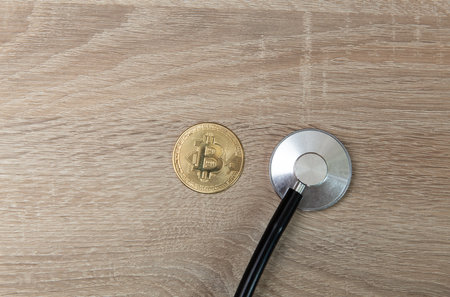 Stethoscope with bitcoin on wooden tableの写真素材