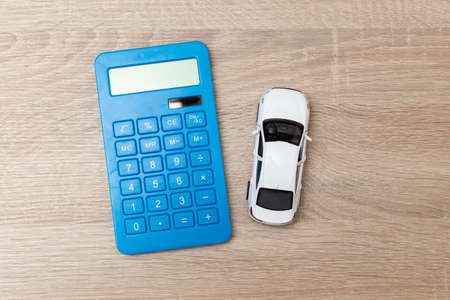 Calculator with toy car model on wooden tableの写真素材