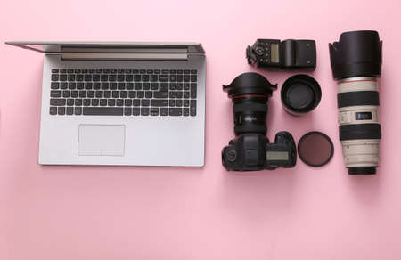 Set of professional photographic equipment (camera with lenses) with laptop on a pink background. top view. flat layの写真素材