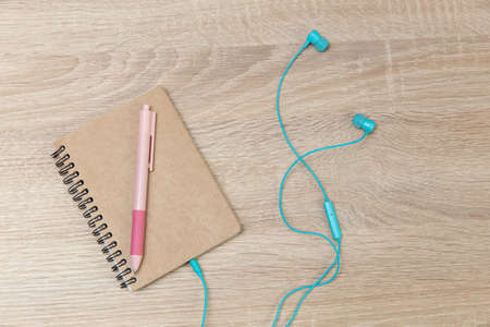 Notebook with headphones on a wooden tableの写真素材