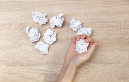 Hand holds crumpled sheets of paper on wooden tableの写真素材