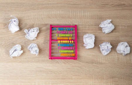 Abacus among crumpled sheets of paper on wooden table. business concept