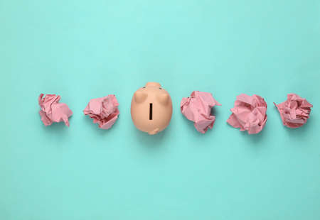 Piggy bank with crumpled paper balls on blue backgroundの写真素材