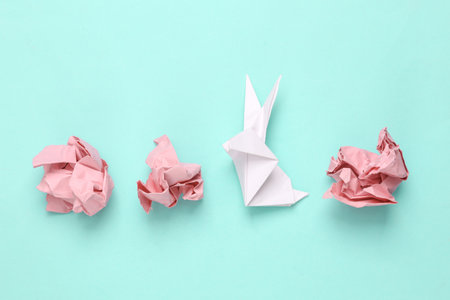 Crumpled pink paper with origami rabbit on a blue background. easter symbolの写真素材