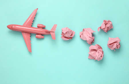 Pink plane with crumpled sheets of paper on blue background. travel symbolの写真素材