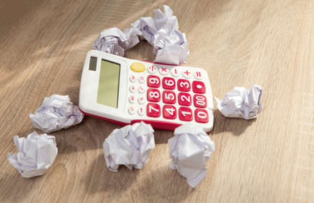 Calculator among crumpled sheets of paper on wooden table. business conceptの写真素材