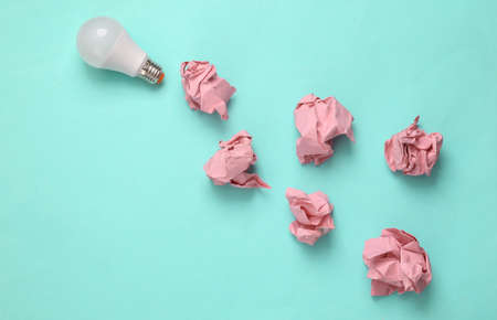 Light bulb with crumpled paper balls on blue background. creative ideas