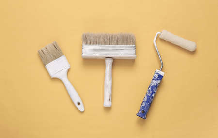 Paint brushes and rollers on yellow background. Repair symbol