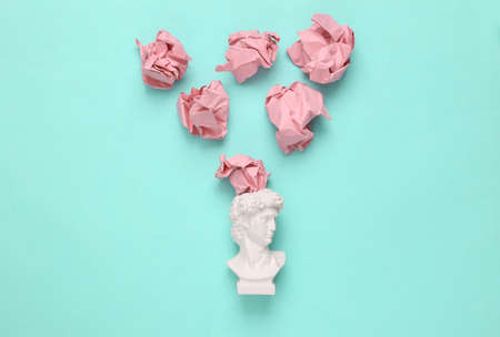 David bust with crumpled paper balls on blue background. minimal layoutの写真素材