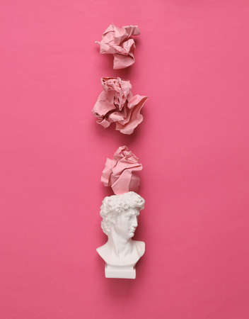 David bust with crumpled paper balls on pink background. minimal layoutの写真素材