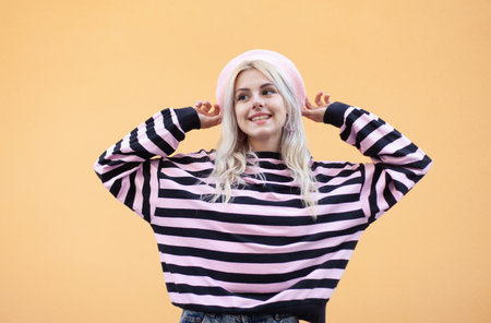 Emotional smiling girl in a beret and sweater having fun on a yellow background. Portrait of cool hipster woman in trendy outfit. lifestyleの写真素材