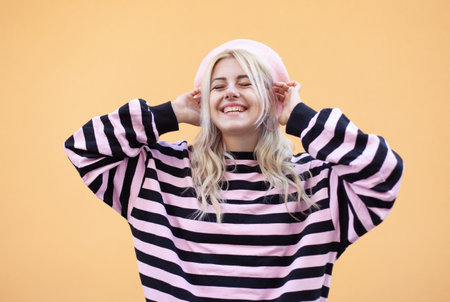 Emotional smiling girl in a beret and sweater having fun on a yellow background. Portrait of cool hipster woman in trendy outfit. lifestyleの写真素材
