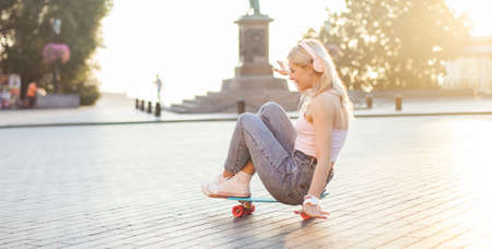 Cute cool girl is riding while sitting on a skateboard
