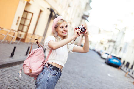 Charming hipster girl in beret with retro camera in city. Travel concept, lifestyle. french styleの写真素材