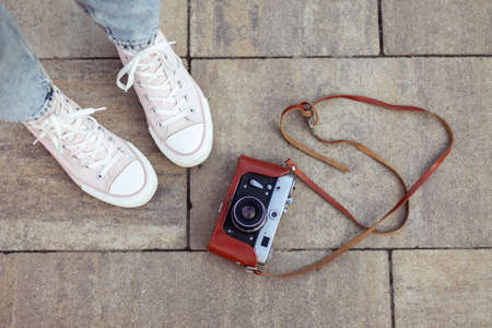Women's legs in sneakers and retro camera.の写真素材