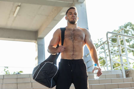 Fitness man with exercise bag and water bottle outdoors