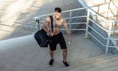 Fitness man with exercise bag and water bottle outdoorsの写真素材