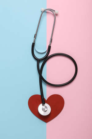 Stethoscope with heart on blue pink background. Cardiovascular disease diagnosis, love concept. top...