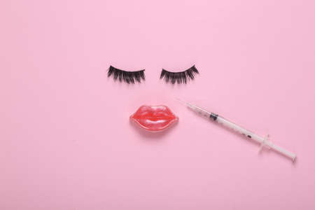 Face of false eyelashes and lips, injection syringe with hyaluronic acid on pink background. Lip...