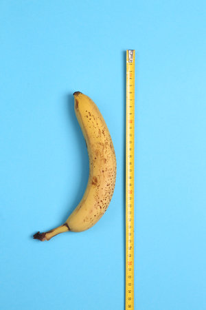 Banana with a ruler on a light blue background. top view. sex conceptの写真素材