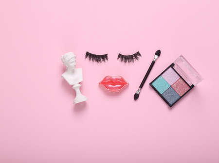 False eyelashes with lips in the shape of a face and eyeshadow palette, venus bust on pink background. Beauty minimal still life. flat layの写真素材