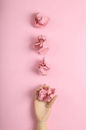 Hand holds crumpled sheets of paper on a pink background. Minimal flat lay still lifeの写真素材