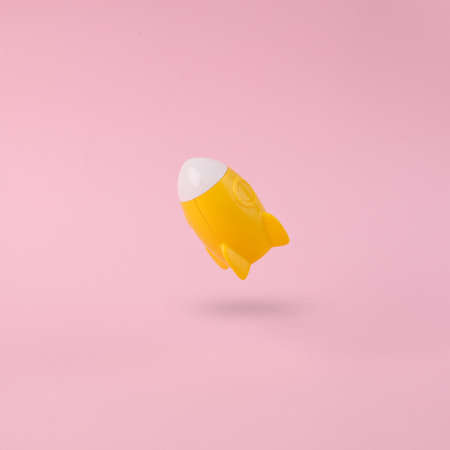Take off yellow space shuttle or rocket on a pink background with shadows. Minimalism, conceptual...