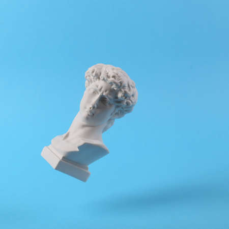 Levitating Antique Plaster bust of David on blue background. concept pop. Minimal still life...