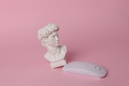 Antique bust of David with modern pc mouse on pink background. Minimal still lifeの写真素材