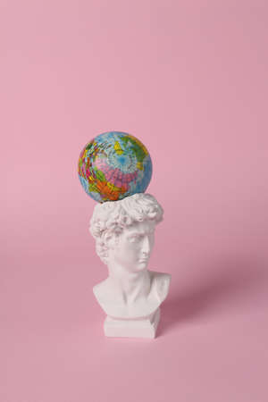 Antique David bust with globe on pink background. concept pop. Minimal still life. creative travel layoutの写真素材