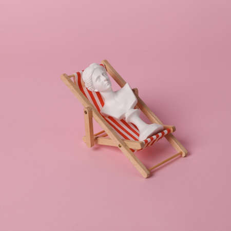 Perfect vacation concept. Venus Bust rests on beach deck chair. pink background. Minimal still life