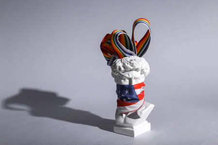 David bust with usa flag on his face and lgbt rainbow tape on gray background. Minimal still life