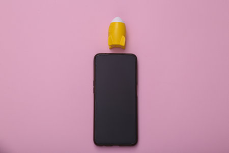 Smartphone with a rocket on a pink background. Speed up your smartphone