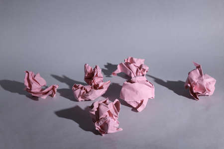 Pink crumpled paper balls on gray background with shadow
