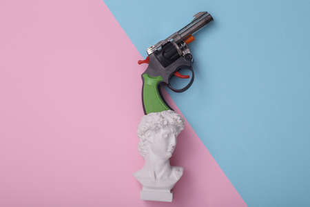 David bust with gun on pink blue background. creative layout. Minimal still life. flat lay. top viewの写真素材