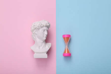 David bust with hourglass on pink blue background. creative layout. Minimal still life. flat lay. top viewの写真素材