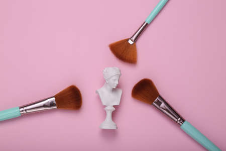 Venus Bust with makeup brushes on pink background. Minimal beauty still life. flat layの写真素材