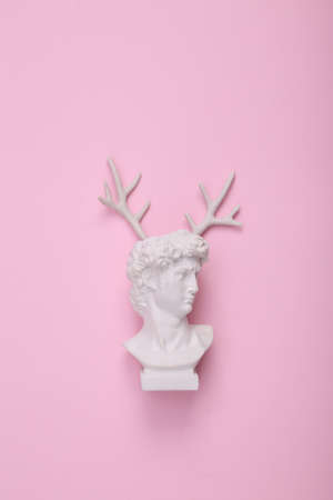 David bust with antlers on pink background. creative layout. concept pop. Minimal shopping still...