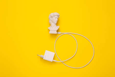 David bust with charger on yellow background. Minimal still life photo. top viewの写真素材