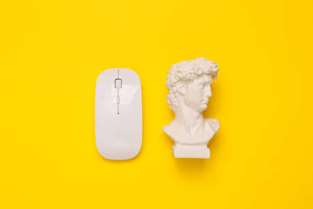 Minimal still life. Antique David bust with pc mouse on yellow backgroundの写真素材