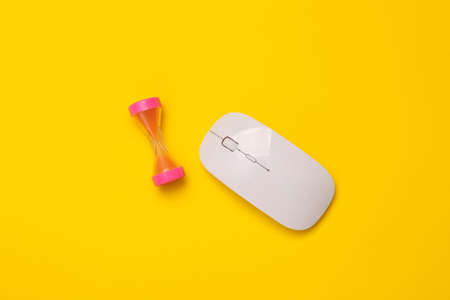 Pc mouse with hourglass on yellow background. top view