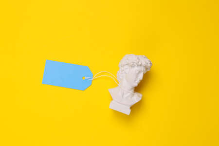 David Bust with tag on yellow background. Minimal still life. flat layの写真素材