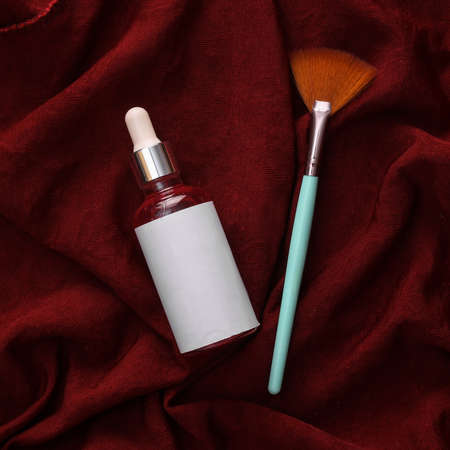 Face serum bottle and brush on red silk backgroundの写真素材