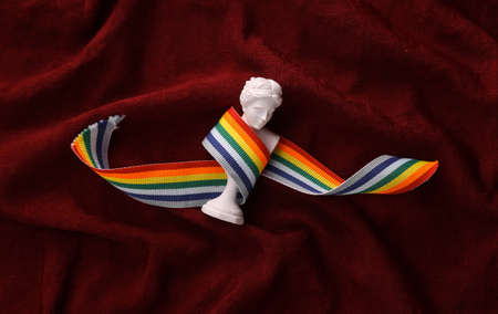 Venus plaster bust with lgbt rainbow tape on red crumpled silk background